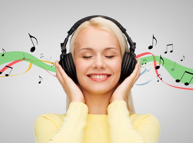 conceito de música e tecnologia - jovem sorridente com os olhos fechados ouvindo música com fones de ouvido