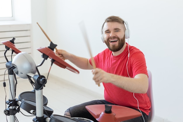 Foto conceito de música, hobby e pessoas - baterista de jovem tocando bateria eletrônica.