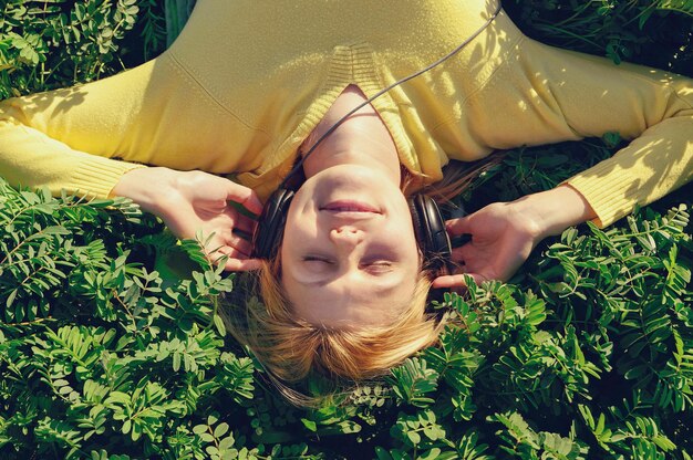 Conceito de música. Mulher jovem com fones de ouvido ouvindo música em um prado