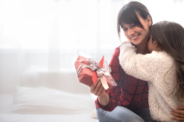 Foto conceito de natal, a filha dá um presente para sua mãe