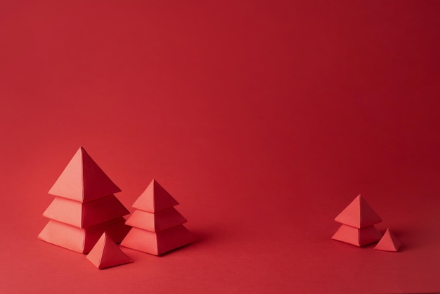 Conceito de Natal, cartão de Natal, cinco árvores de Natal vermelhas feitas de papel sobre fundo vermelho, close-up.