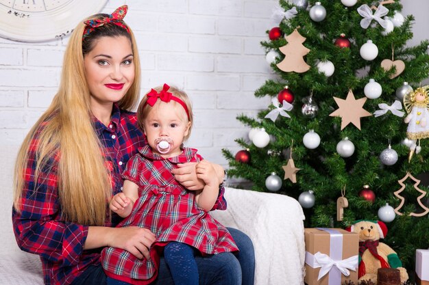 Conceito de Natal e família - jovem mulher com filha e árvore de Natal decorada