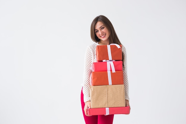 Conceito de natal e feriados - jovem segurando uma pilha de caixas de presente sobre um fundo branco com espaço de cópia