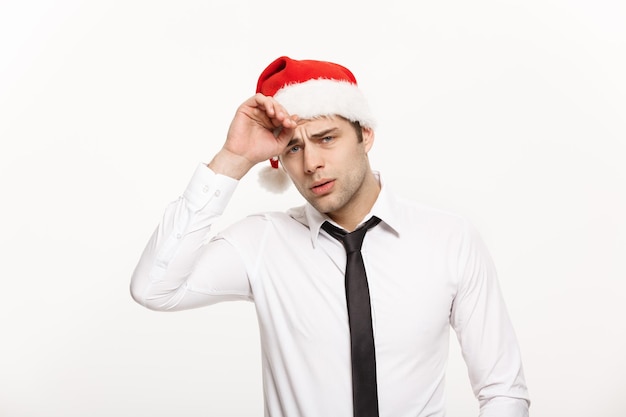 Conceito de Natal Homem de negócios bonito usa chapéu de Papai Noel posando com expressão facial estressante em fundo branco isolado