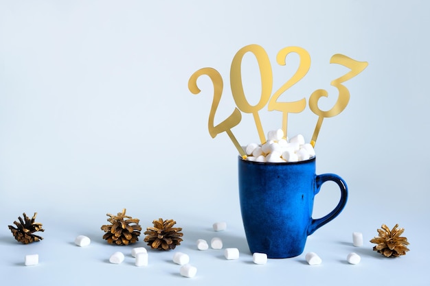 Conceito de Natal ou Ano Novo 2023 Caneca azul de cacau com marshmallows e números dourados 2023 espaço de cópia