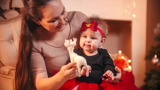 Conceito de natal uma jovem sorridente sentada na cadeira com sua filha no estúdio de natal