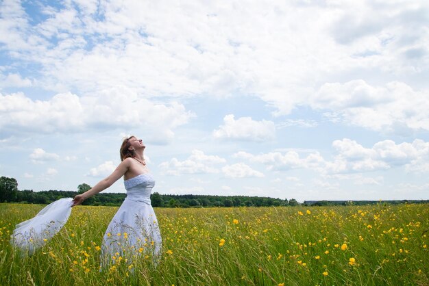 Conceito de natureza beleza do dia do casamento no meio do campo há uma mulher incrível usando vestido de noiva branco ela está girando em torno de si mesma e lantejoulas estão brilhando à luz do sol