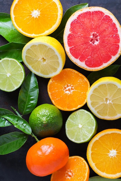 Conceito de natureza de nutrição de dieta alimentar saudável Fundo de vitamina de frutas cítricas Toranja laranja tangerina limão com folhas em uma mesa preta grunge Vista superior plana em cima