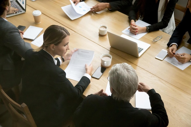 Conceito de negociações diferentes empresários discutindo detalhes do negócio em reunião de grupo jovens e antigos parceiros equipe pensando falando consultoria sobre contrato sentado na mesa do escritório de conferência