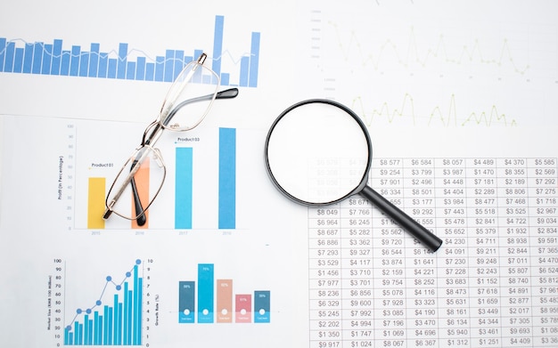 Conceito de negócio com lápis de óculos de calculadora e lupa em documentos. Gráficos e gráficos de negócios