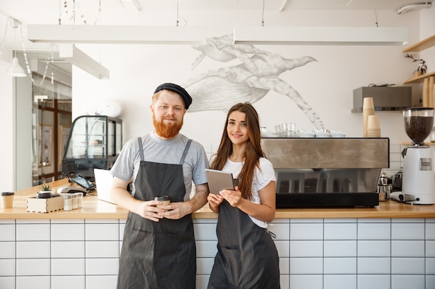 Conceito de negócio de café - baristas de barman felizes prontos para dar serviço na moderna cafeteria.