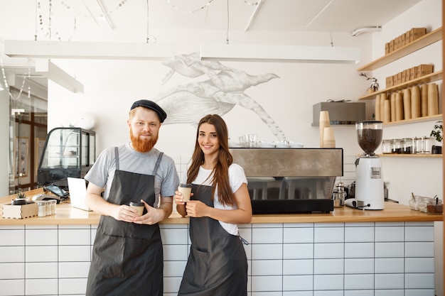 Conceito de negócio de café - retrato de pequenos parceiros de negócios em pé juntos em sua loja de café