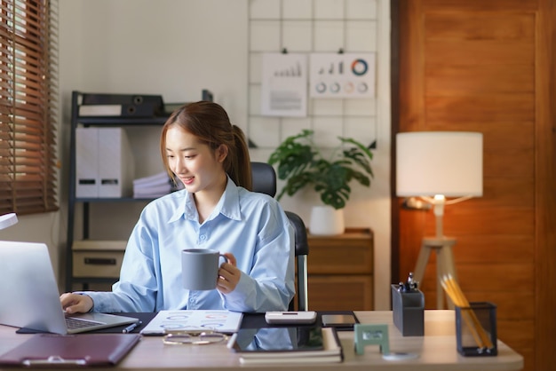 Conceito de negócio de inicialização As empresárias estão bebendo café e digitando dados no laptop no local de trabalho