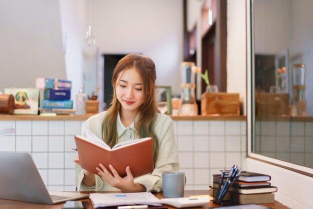 Conceito de negócio Mulher empreendedora lendo um livro enquanto trabalhava no escritório do espaço de coworking