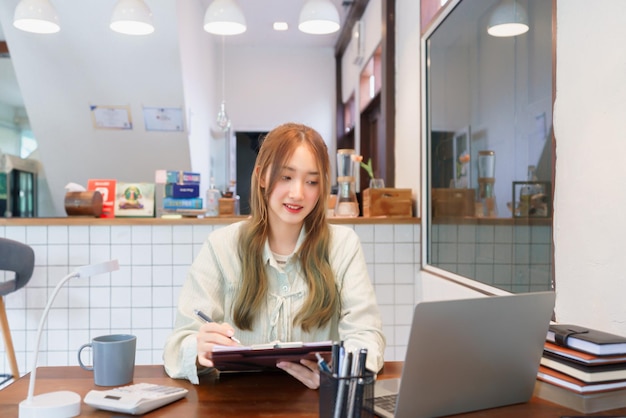 Conceito de negócio Mulher empreendedora trabalhando em laptop com calculadora no escritório de espaço de coworking