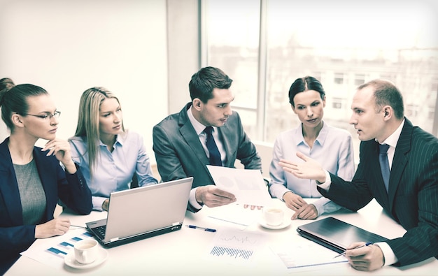 conceito de negócio, tecnologia e escritório - equipe de negócios sorridente com laptops, documentos e café discutindo no escritório