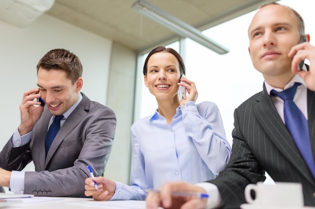 conceito de negócio, tecnologia e escritório - equipe de negócios sorridente com smartphones fazendo ligações no escritório