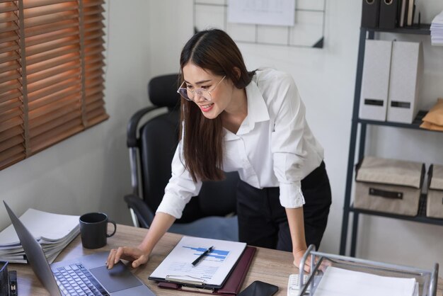 Conceito de negócios A empresária está digitando para pesquisar dados e ler o relatório de negócios no laptop