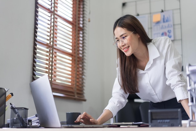 Conceito de negócios A empresária está digitando para pesquisar dados e ler o relatório de negócios no laptop