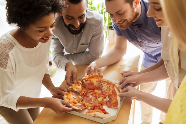 conceito de negócios, comida, almoço e pessoas - equipe de negócios feliz comendo pizza no escritório