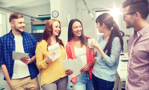 Foto conceito de negócios, comunicação, inicialização e pessoas - feliz equipe criativa internacional ou estudantes no intervalo para café conversando no escritório