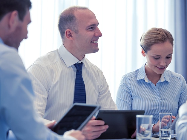 conceito de negócios, conferências, pessoas, tecnologia e trabalho em equipe - empresários e empresária sorridentes com reunião de computador tablet pc no escritório