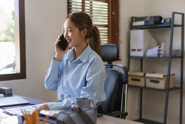 Conceito de negócios de inicialização As empresárias estão falando no smartphone e trabalhando no local de trabalho