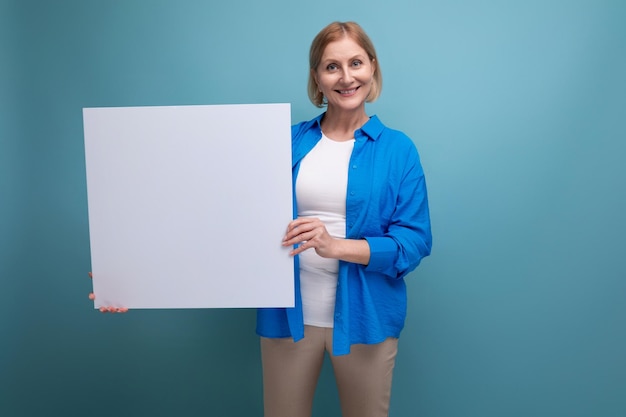 Conceito de negócios de meia-idade mulher de meia-idade segurando um cartaz para notas com um mocap em um azul
