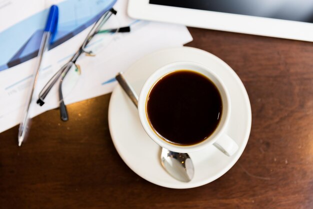 conceito de negócios e bebidas - close-up da xícara de café, gráficos e tablet pc na mesa