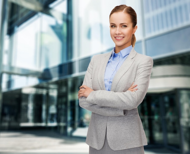 conceito de negócios e educação - simpática jovem empresária sorridente com braços cruzados