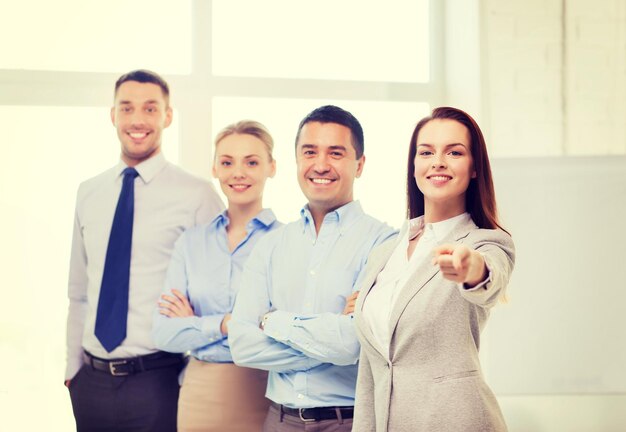 Foto conceito de negócios e escritório - empresária bonita sorridente com equipe no escritório apontando o dedo para você