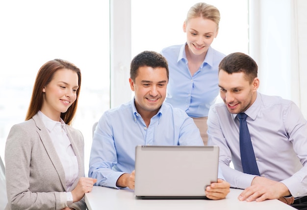 Conceito de negócios e escritório - equipe de negócios sorridente trabalhando com computador portátil no escritório