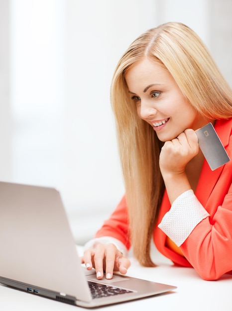 Conceito de negócios e internet - mulher de negócios sorridente com laptop usando cartão de crédito