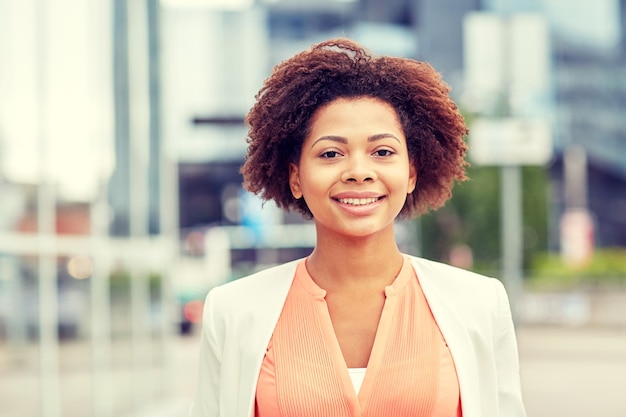 conceito de negócios e pessoas - jovem empresária afro-americana sorridente na cidade