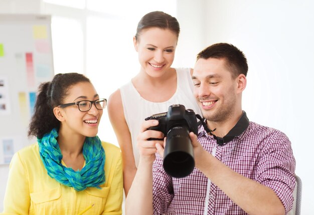 conceito de negócios, educação, escritório e inicialização - equipe criativa sorridente com câmera fotográfica trabalhando no escritório