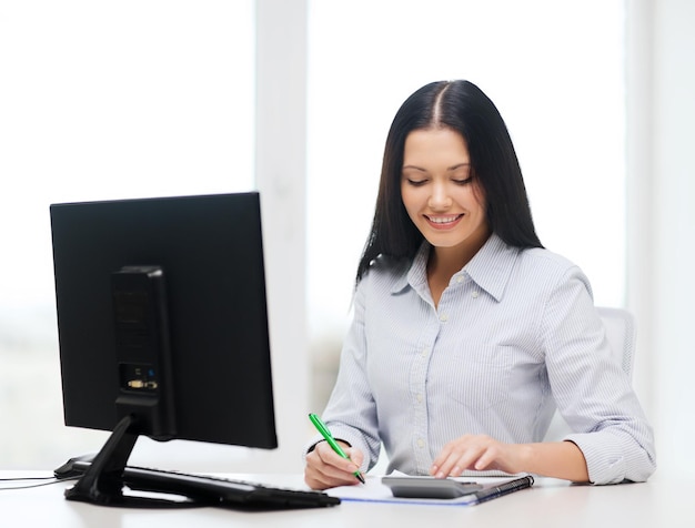 conceito de negócios, educação, tecnologia e impostos - sorridente mulher de negócios ou estudante com coputer, calculadora, caderno e caneta