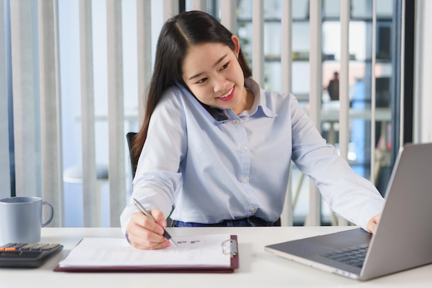 Conceito de negócios Empresária conversando com cliente no smartphone e anotando dados no documento