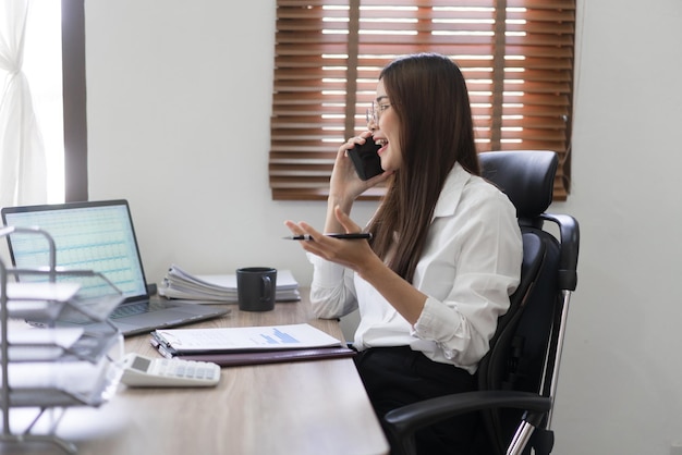 Conceito de negócios Empresária está falando de dados financeiros com parceiro em smartphone no escritório