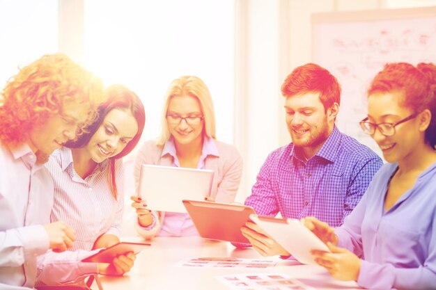 conceito de negócios, escritório e inicialização - equipe criativa sorridente com computadores de mesa e papéis trabalhando no escritório