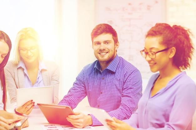 Foto conceito de negócios, escritório e inicialização - equipe criativa sorridente com computadores de mesa e papéis trabalhando no escritório