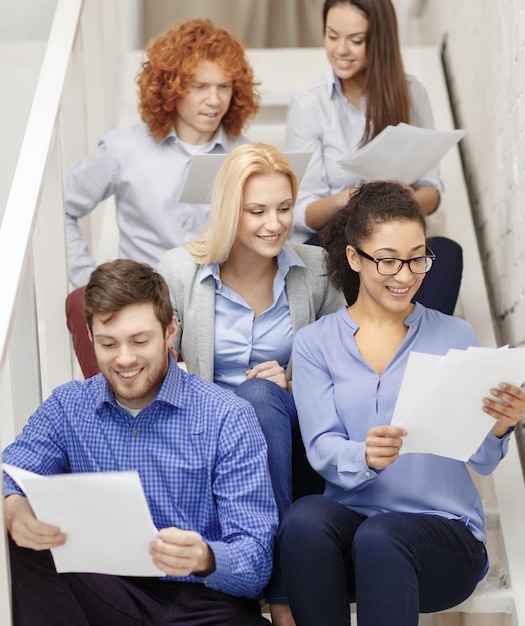 Foto conceito de negócios, escritório e inicialização - equipe criativa sorridente com papéis e café na escada