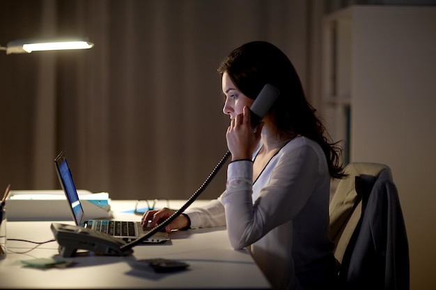 conceito de negócios, excesso de trabalho, prazo e pessoas - mulher digitando no laptop e ligando no escritório noturno