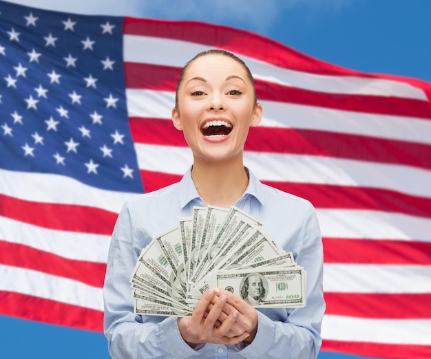 conceito de negócios, feriados e pessoas - empresária rindo com dinheiro em dinheiro dólar sobre fundo de bandeira americana