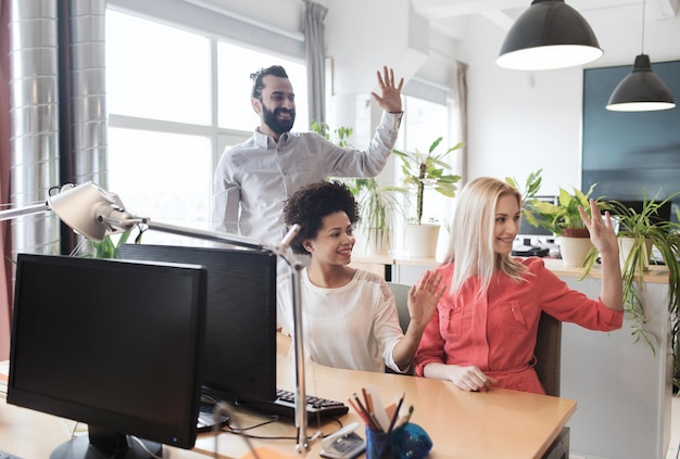Foto conceito de negócios, inicialização e escritório - equipe criativa feliz acenando as mãos no escritório