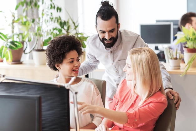 Foto conceito de negócios, inicialização e pessoas - equipe criativa feliz com computador discutindo algo no escritório