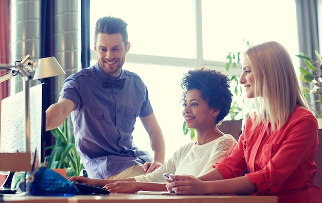 conceito de negócios, inicialização e pessoas - rede de equipe criativa feliz com computador no escritório