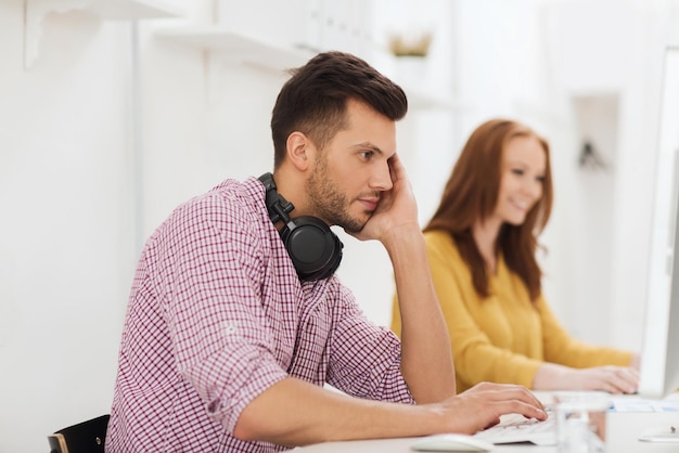 conceito de negócios, inicialização, educação, tecnologia e pessoas - equipe criativa ou estudantes com fones de ouvido e computador no escritório