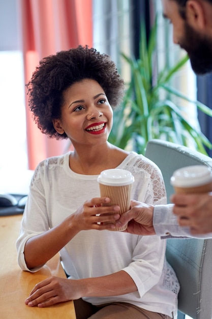 conceito de negócios, inicialização, pessoas e bebidas - mulher africana feliz tomando café do homem no escritório