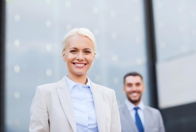 conceito de negócios, parceria, sucesso e pessoas - close-up do empresário sorridente e empresária em cima do prédio de escritórios