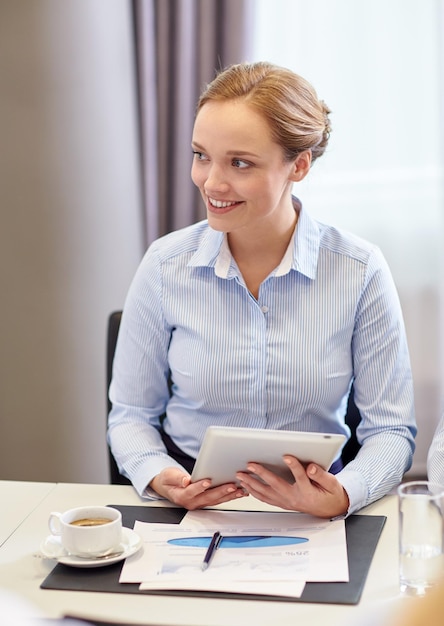 conceito de negócios, pessoas e tecnologia - mulher sorridente com computador tablet pc, papéis e xícara de café no escritório